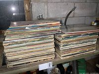 Photo showing two large stacks of vintage LP records on a shelf, some record covers showing edge wear.