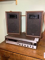 Full view of vintage stereo tuner with two standing speakers on top, showing wood finish and fabric grills on speakers.