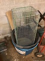 Large rectangular wire mesh cage placed inside a blue plastic tub, measuring roughly 12x14x36 inches, showing some wear.