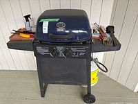 Full view of grill, propane tank and utensils on side shelves