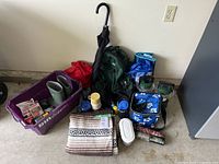 Group view of all camping items including backpack, boots, lanterns, mugs, blanket, umbrellas, cooler bag and accessories