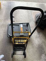 Top view showing black hand truck, yellow luggage trolley nested, and platform cart