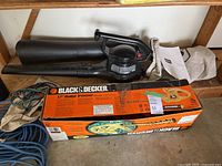 Toro blower-vac, tubes, Black & Decker hedge trimmer box visible on shelf