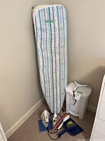 Ironing board, iron, garbage can, dustpan, brush and caulking gun grouped in corner