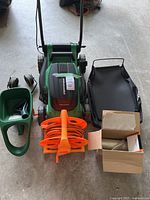 Overall lot showing mower, cord, spreader, earmuffs, bag and box