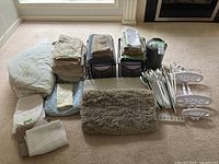 All items laid out showing mattress pad, sheets, towels, mats, hangers, wastebasket, storage cubes, shower caddy