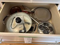 Drawer overview showing electric skillet, splatter screens, egg poacher and other pans