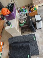 Overview of lot showing shoe shelves, mats, trash can, side table, tote with items