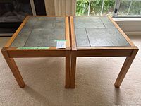 Both matching wood frame tile-top side tables side by side