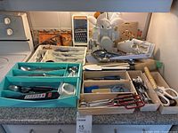 Overall countertop view with trays of cutlery, utensil stand, graters, electric carving knife and cookbooks