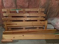 Stack of pine slat panels and rails leaning against insulated wall