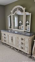 Full view of antique-style cream Pulaski chest with marble top, showing detailed carvings, metal legs, and triple attached mirrors.