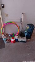 Overview photo showing multiple camping and children's play items including hula hoops, a blanket, water coolers, bowling set, fishing rods, net, and foldable chair in carrying case