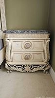 Front view of Pulaski wooden nightstand with classical carvings and grey marble top.