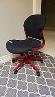 Front angle view of the dark red and black office chair showing the padded seat and backrest with caster wheels on a five-star base.