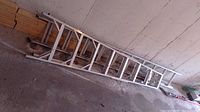 Aluminum extension ladder folded and leaning against wall