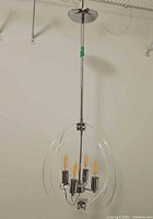 Full view of the modern pendant light hanging, showing chrome finish and clear acrylic encasing with four LED bulbs.