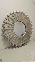 Angle view of the silver sunburst mirror showing the textured rays and circular center mirror.