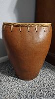 Front angle view of the brown clay vase showing its full body and braided rim detail.