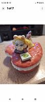 Front view of heart-shaped trinket box with Miss Piggy figurine lying on top, holding a green card.