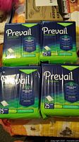 Four sealed packages of Prevail Underpads arranged on a flat surface showing front packaging