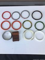 Photo of 12 bracelets laid out on white background showing variety of colors and materials.