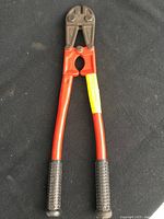 Front view of the 18-inch bolt cutter with red handles and black grips, tool laid flat on a black surface.