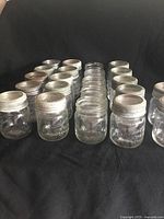 25 vintage canning jars arranged in rows, showing metal lids and glass tops with metal rings.
