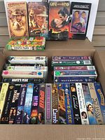 Overview of many VHS tapes, including Raiders of the Lost Ark, Indiana Jones and the Last Crusade, Gone with the Wind, South Park, and others showing box condition and variety.