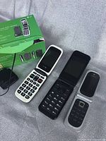 Front view of three flip phones: Doro white with large buttons, ZTE black with external screen, Nokia silver-black with external display, along with green product packaging.