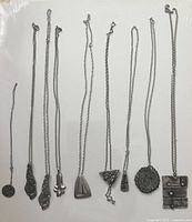 Nine metal chains laid out with varied pewter pendants showing size, shape, and chain style