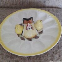 Front view of deviled egg plate showing molded egg compartments, yellow rim, and central chicken figure with two small yellow chicken shakers