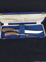 Carving knife and fork set in original blue case, showing knife blade, handles and storage slot