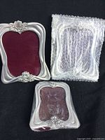 Three Blue Mist pewter picture frames including two wrapped and one open showing burgundy velvet backing and rose embellishments.