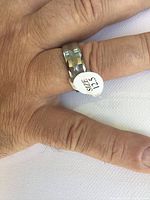 Close-up photo of men's tungsten faceted ring on finger size 12.5 with white size sticker on top