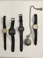 Full lot photo with 4 wristwatches and 1 pocket watch on white background, showing straps and faces