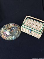 Photo of closed woven wicker sewing basket next to circular container with thread spools