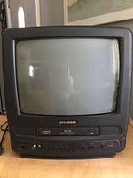 Front view showing CRT screen with VHS player, control buttons, and RCA inputs on the front panel