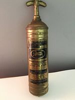 Full view of vintage brass fire extinguisher showing the pump handle, body, and label with Pyrene branding.