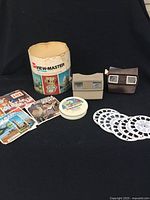 Vintage View-Master set including 2 viewers, 14 reels, original cylindrical container, and printed material.