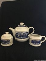 Three-piece ceramic set of teapot, creamer, and sugar bowl with white and blue design.