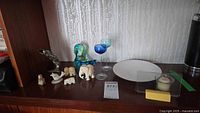 Overall shelf view showing crystal duck, shell fish, stone animals, candle holders, dish