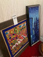 Both framed artworks standing against wall on carpet