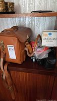 Leather camera bag, lens box, cameras and accessories on shelf