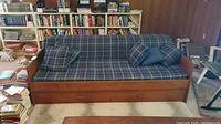 Front view of wood framed sofa with plaid cushion and pillows