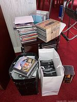 Stack of jewel case CDs, multi-disc box set, black and white bags containing CDs and Pioneer magazines