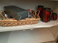 Box containing cognac pipe and wicker basket with ceramics in cabinet