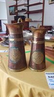 Two hammered copper pitchers showing size and decorative details