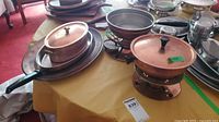 Overview of copper pieces on table: chafing dish, casserole pot, frying pan, tray