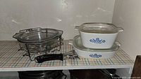 Overall lot showing glass casserole with caddy, two CorningWare dishes with lids, snap-on handle